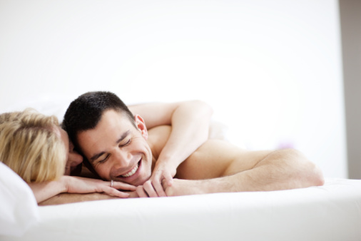 Smiling couple lying together on a bed.