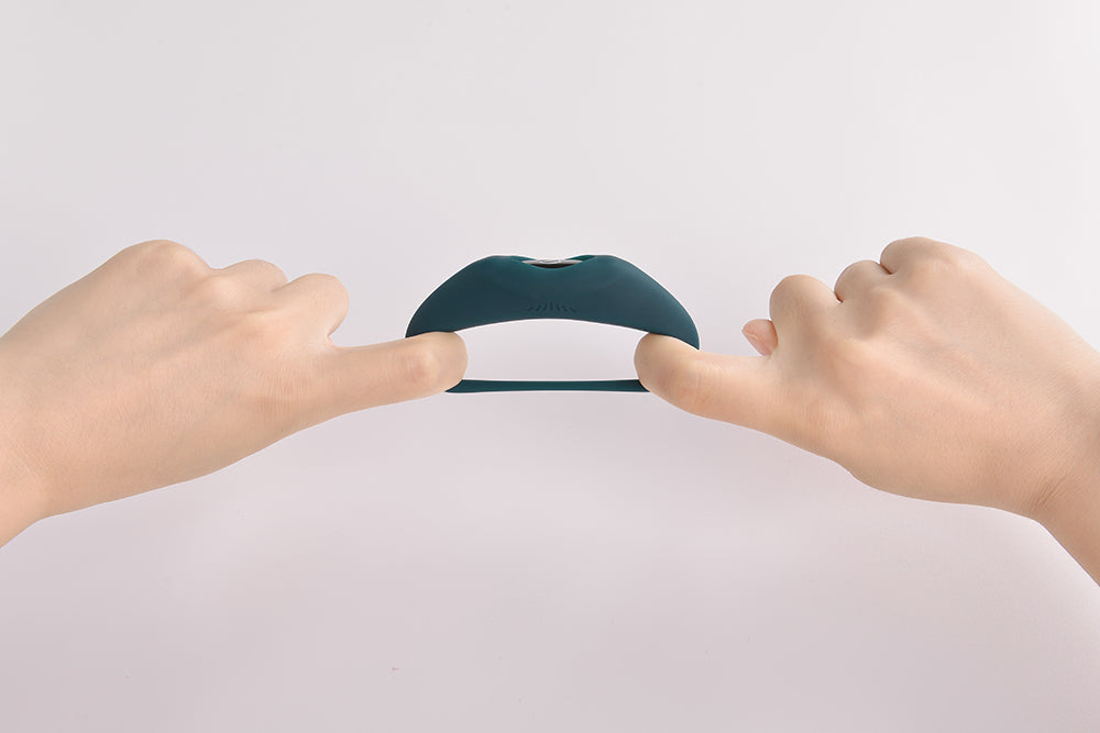 Hands stretching a dark green wearable vibrator.