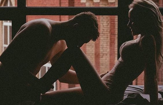 Silhouetted couple sitting together by a window.