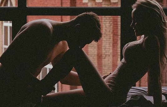 Silhouetted couple sitting together by a window.