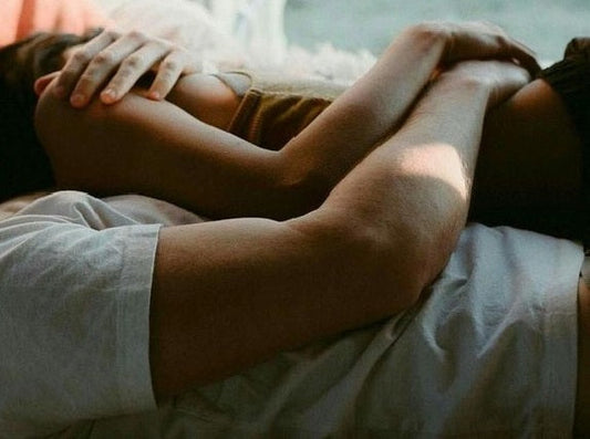 Couple embracing on a bed.