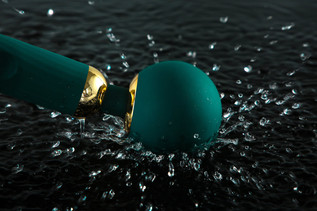 Green wand vibrator splashing through water.