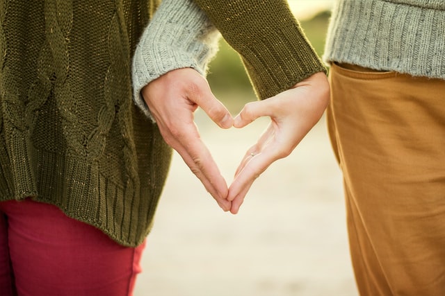 Two people forming a heart shape with their hands.