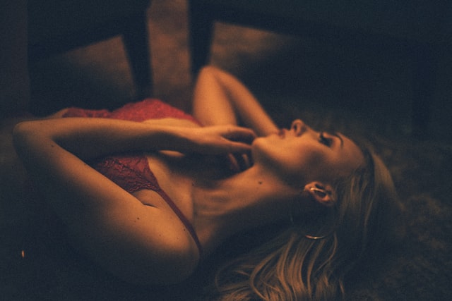Woman in red lingerie reclining in low light.