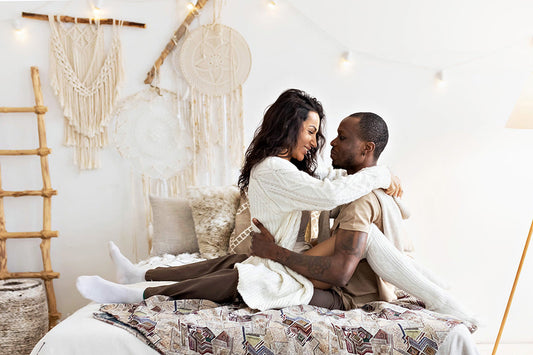 Couple embracing on a bed in a bright room.