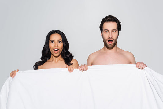 Surprised couple holding a white sheet.