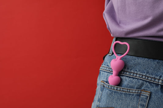Pink heart-shaped toy hanging from a jeans pocket.