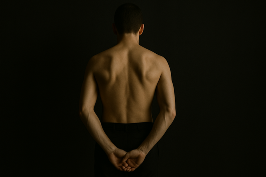 Back view of a shirtless man with hands clasped behind him.