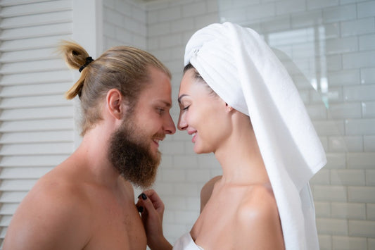 Couple smiling together in a bathroom with a towel.