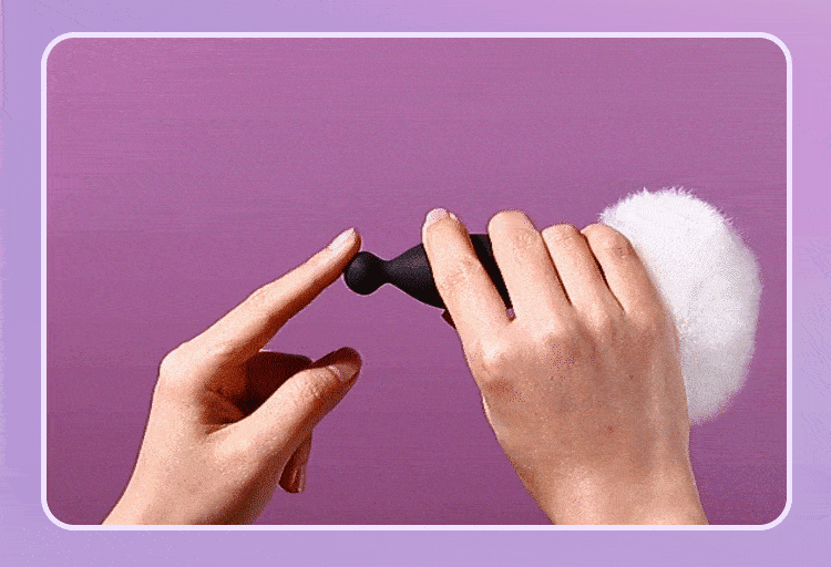 Hands holding a black wearable device against a purple background.