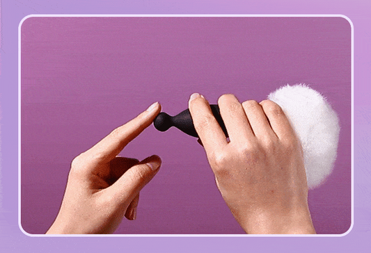 Hands holding a black wearable device against a purple background.