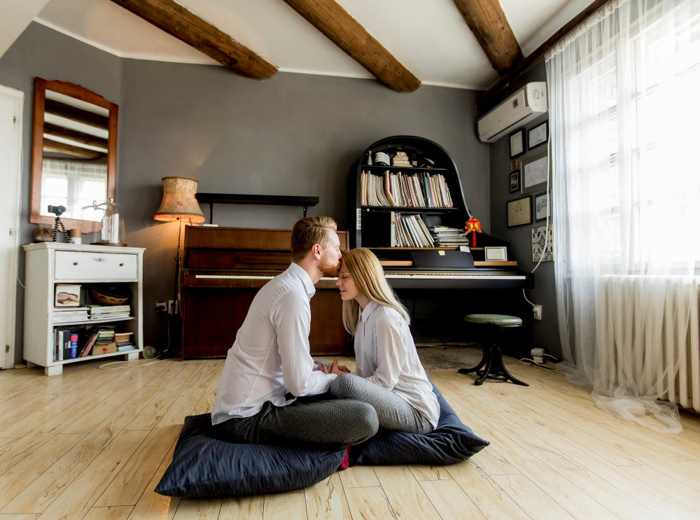 Couple sitting close together on floor cushions.