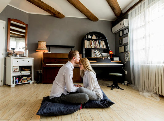 Couple sitting close together on floor cushions.