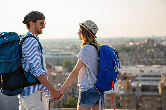 Couple with backpacks holding hands above a city.