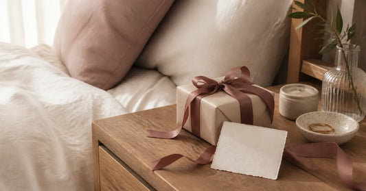 Wrapped intimate gift box with a small card on a bedside table.