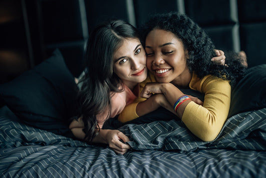 Two women cuddling in bed.