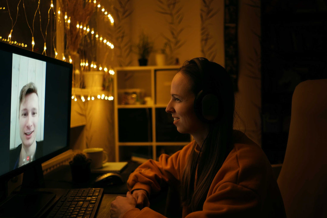 Woman wearing headphones during a video call at a desk.