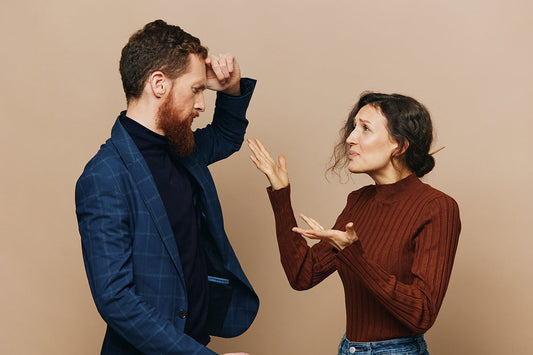 Couple arguing against a beige background.