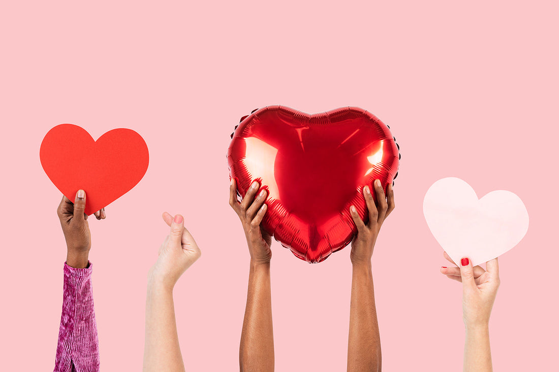 Hands holding red and white heart decorations.