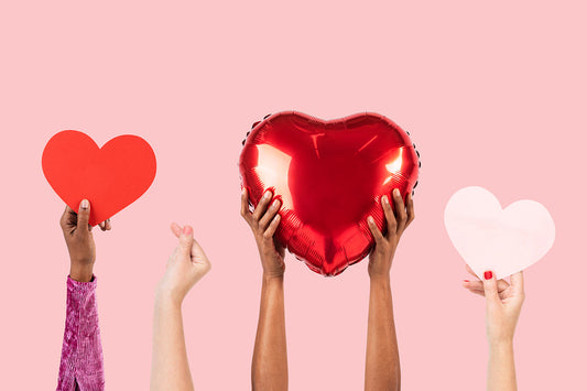 Hands holding red and white heart decorations.