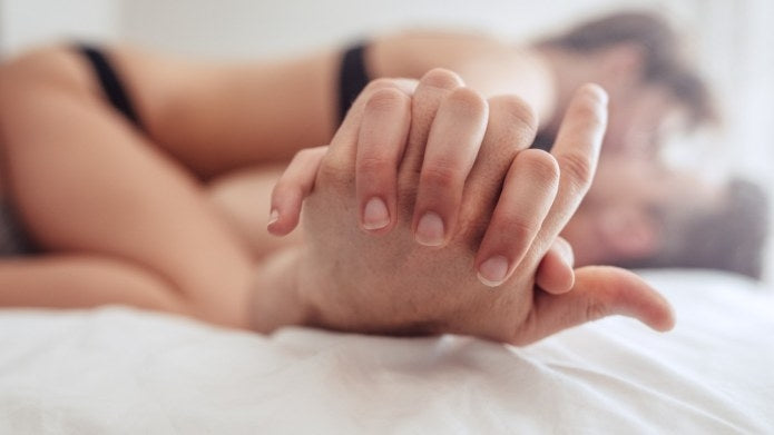 Couple holding hands in bed.