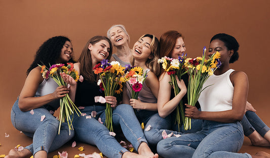 Group of women holding colorful flower bouquets.