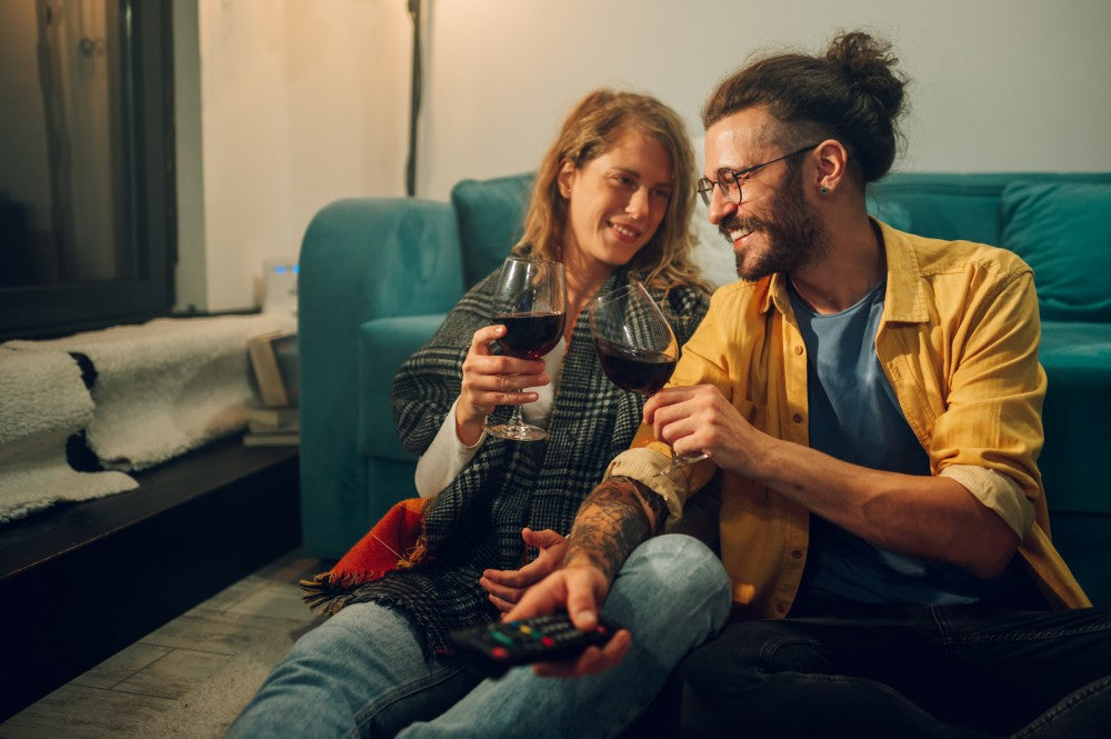 Couple toasting wine while watching television.
