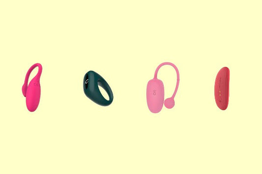Four pink and green wearable vibrators on a pale yellow background.