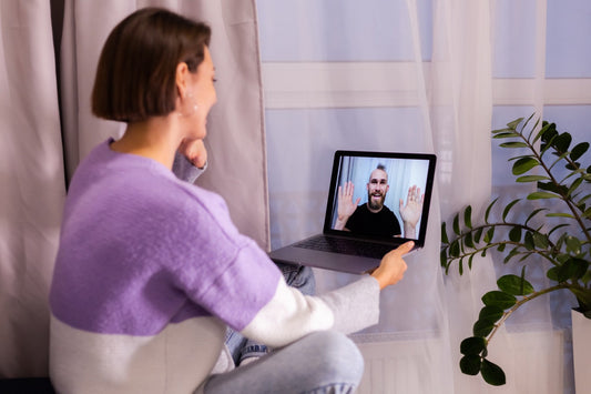 Woman holding a laptop during a video call.