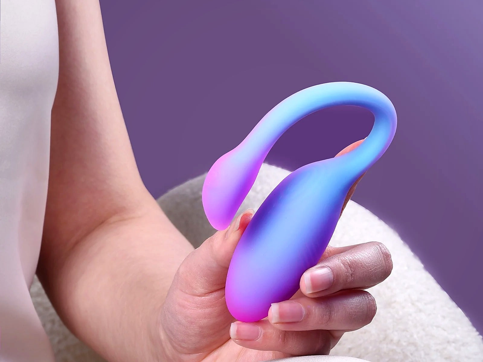 Magic Flamingo Max blue purple gradient wearable vibrator held in one hand against a purple background