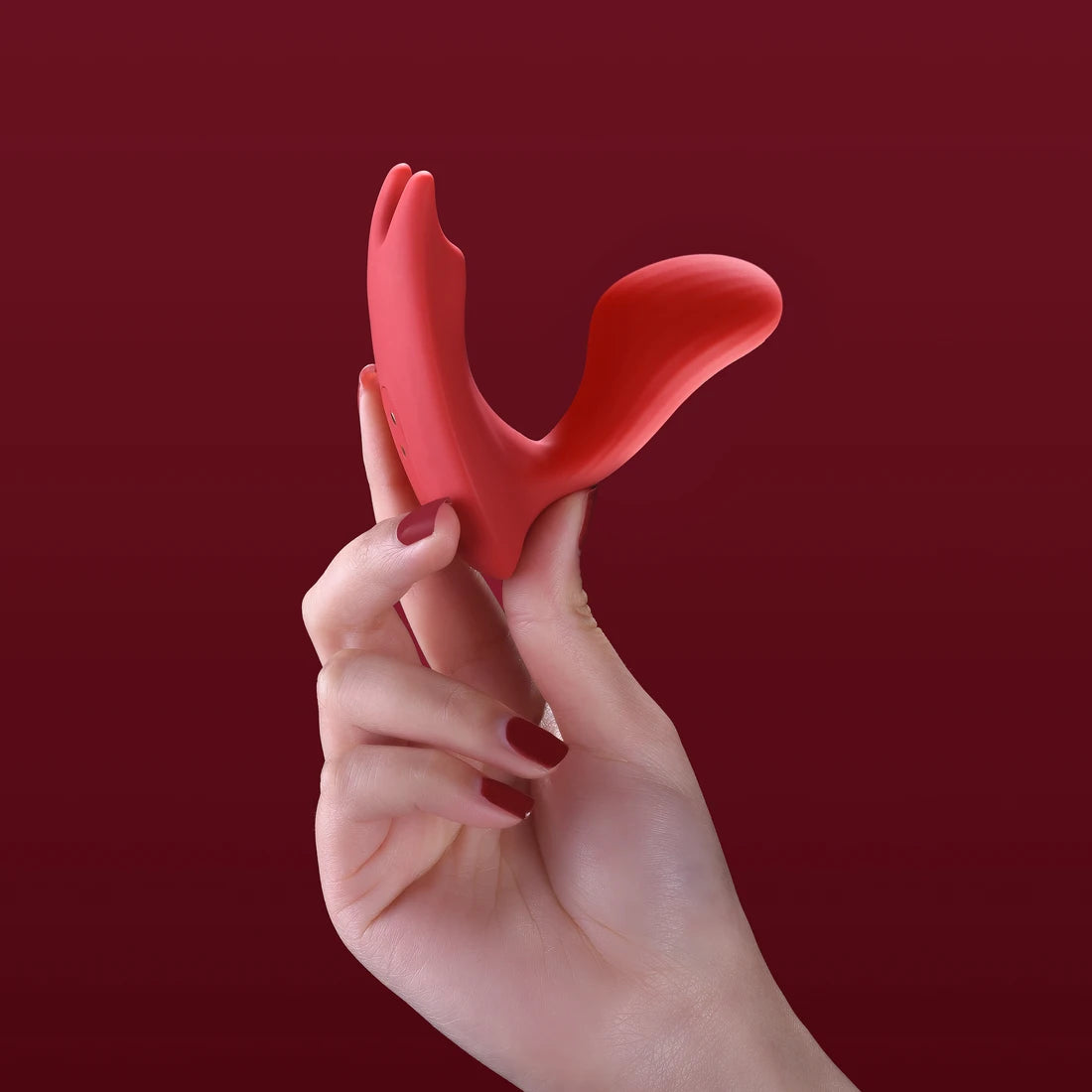 Hand holding red Magic Umi against a deep burgundy background